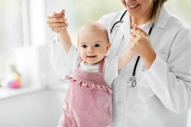 bébé en rose tenu par un médecin souriant