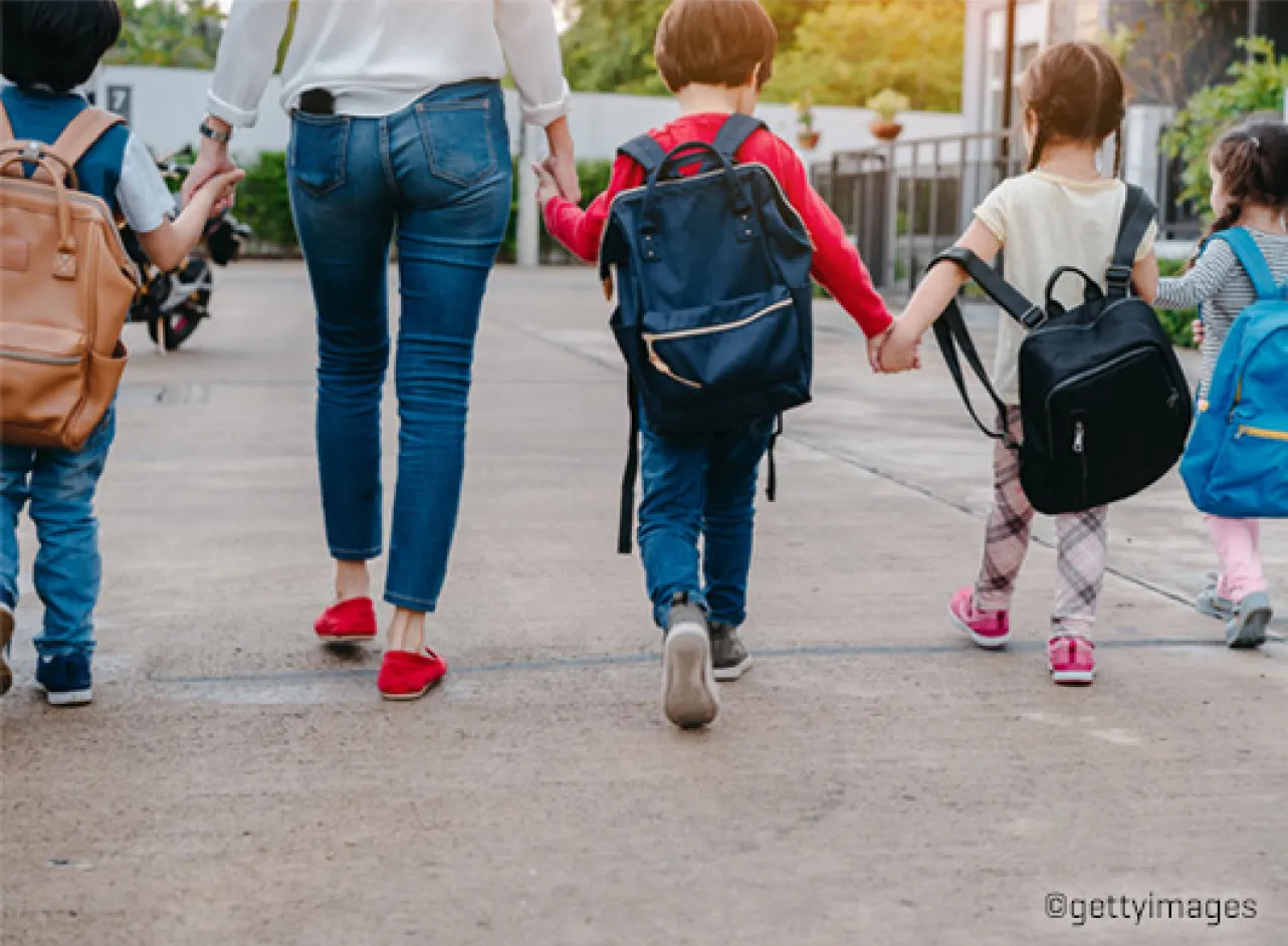 Enfants marchant main dans la main avec un adulte